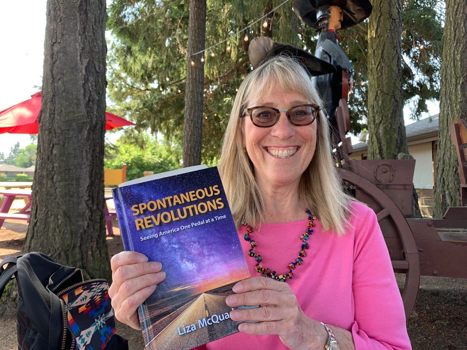 Liza McQuade holding her book, Spontaneous Revolutions